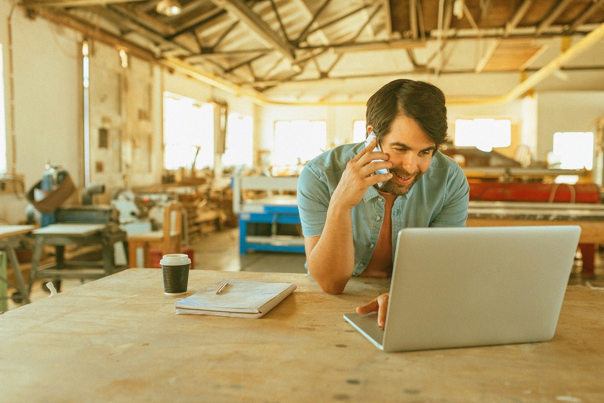 Smiling,Young,Craftsman,Standing,At,A,Workbench,In,His,Large Debt Management